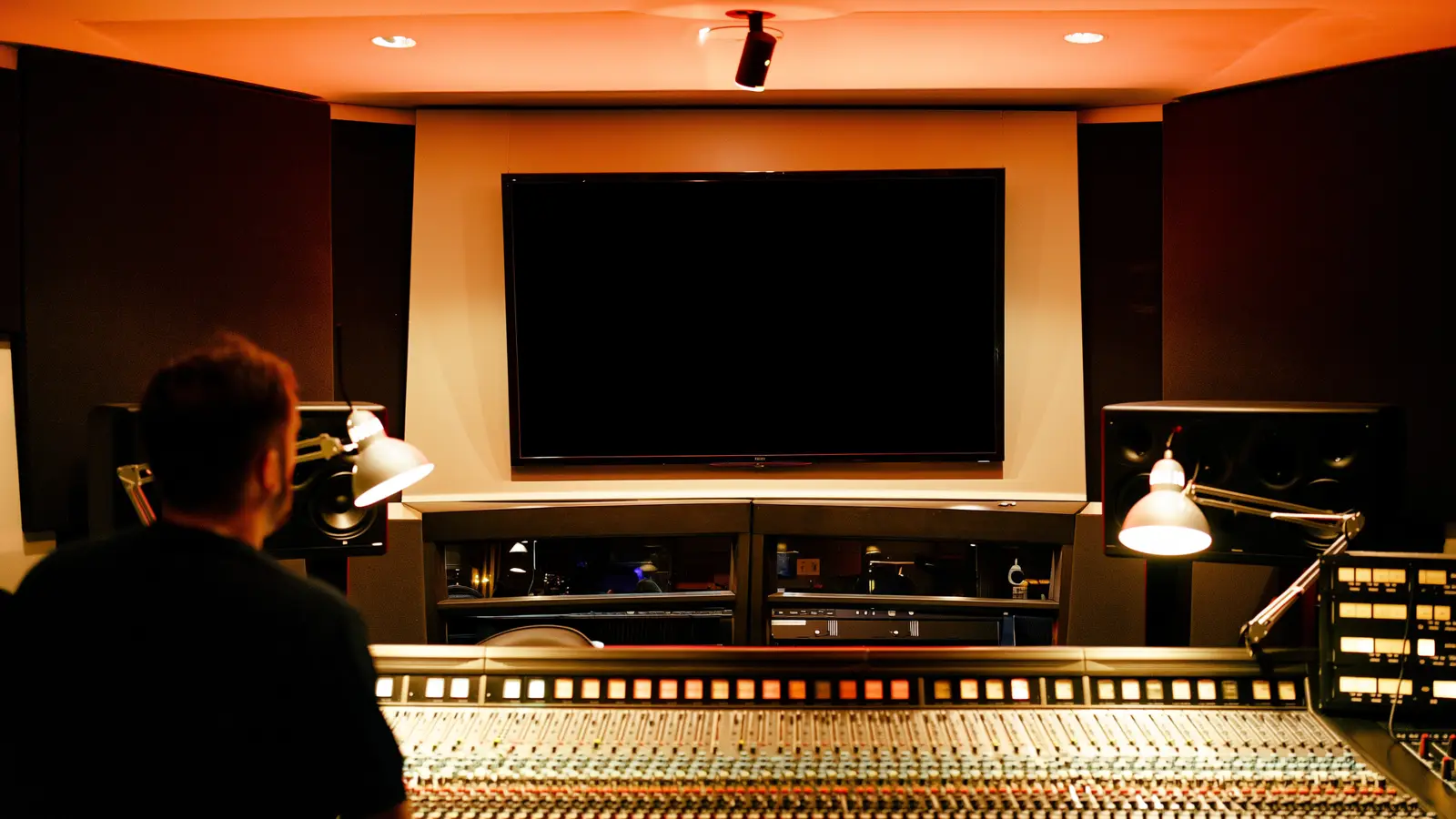 Regieraum eines Tonstudios mit einem ausgeschalteten Bildschirm an der Wand über dem Mischpult
